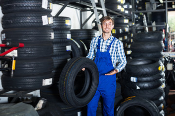 Obraz na płótnie Canvas young friendly mechanic man working with car tires in workshop