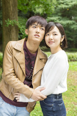 Fototapeta premium カップル 男女 デート 公園 緑 寄り添う 遠くを見つめる
