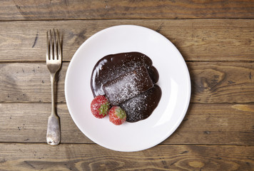 A hot chocolate brownie dessert on a rustic wooden dinner table background