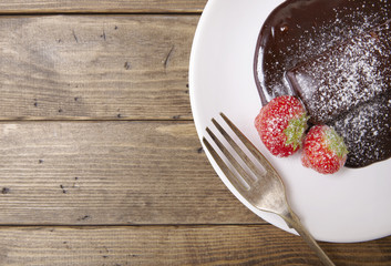 A hot chocolate fudge cake dessert on a reclaimed wooden table background forming a page border