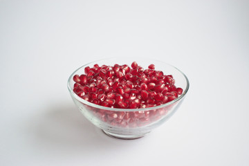 Pomegranate seeds in a bowl on a white background