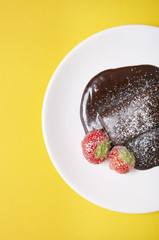 Aerial view of a chocolate fudge cake pudding on a  bright yellow background