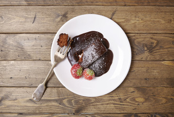 Aerial view of a chocolate fudge cake dessert on a rustic wooden table background