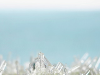 Christmas winter background. Small crystals of ice on the bottom of light blue background. Copy space for your text.