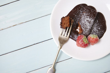 A chocolate fudge cake dessert on a blue wooden table background forming a page border