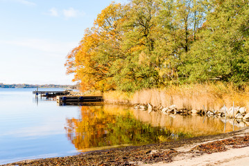 Windless and calm sea in fall with colorful trees and fine weather. Jarnavik just outside Ronneby in Sweden.