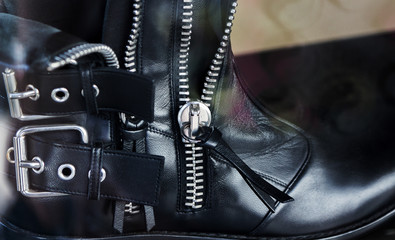detail of black leather boots with zippers and straps