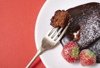 A chocolate fudge cake dessert on a bright red background