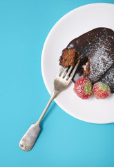 A chocolate fudge cake dessert on a bright blue background