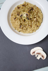 A dinner plate of chicken and mushroom risotto rice on a rustic slate background
