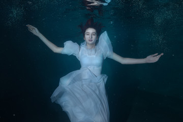 Woman in a white dress under water.