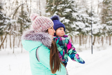 Mother and little toddler girl walking in the winter forest and having fun with snow. Family enjoying winter. Christmas and lifestyle concept.