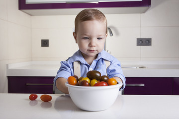 Baby boy playing with ripe colorful cherry tomatoes