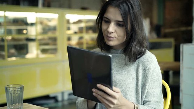 Pretty, young woman using tablet computer sitting in cafe 
