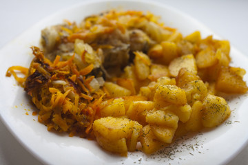 Close-up of fried potatoes with fish in white plate.