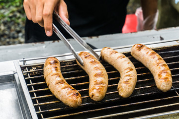 Fresh sausage and hot dogs grilling outdoors on a gas barbecue g