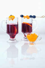 Two glasses of mulled wine with grapes and tangerines on skewers