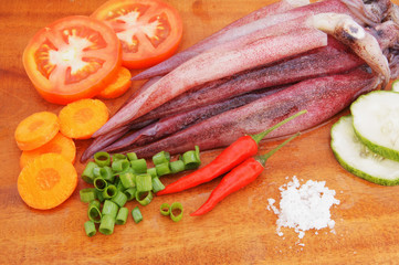 Cooking squids, squids and vegetables on wooden board