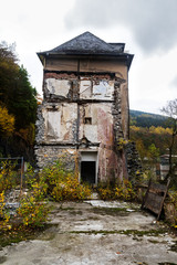Fototapeta na wymiar Decayed house in an autumn landscape, metaphor for old age poverty
