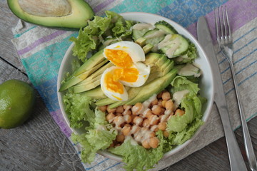 healthy salad in a bowl. avocado, chickpeas, cucumber and egg. more greens every day