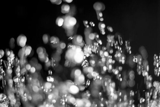 Water drops blurred in motion and defocused on background. Creative flying waterdrops background on black. Drops of water levitate on dark