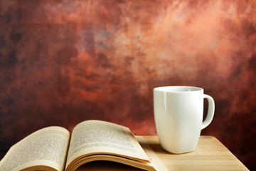 Cup of coffee and book on wooden table