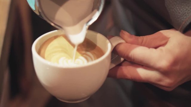 Barista pouring coffee with milk to make art latte. Barista prepares latte in take away white cup, pouring milk. Female hands, portrait. Inside shooting. Cafe business. Coffee industry.