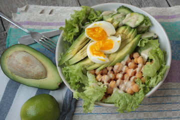 healthy salad in a bowl. avocado, chickpeas, cucumber and egg. more greens every day