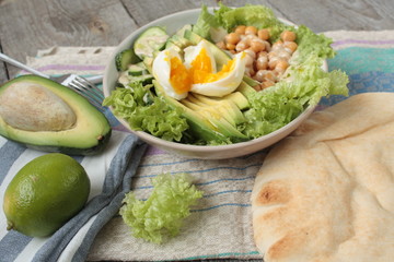 healthy salad in a bowl. avocado, chickpeas, cucumber and egg. more greens every day