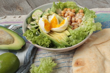 healthy salad in a bowl. avocado, chickpeas, cucumber and egg. more greens every day