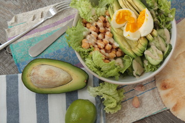 healthy salad in a bowl. avocado, chickpeas, cucumber and egg. more greens every day