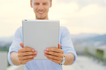 Working on tablet computer. Handsome young man using digital tablet outdoor.