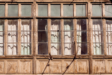 Poor rustic house with huge wooden windows frames in historical city