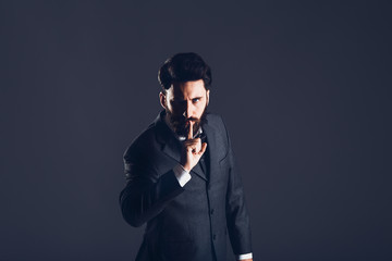 Young handsome bearded caucasian man posing indoors. Perfect skin and hairstyle. Wearing elegant jacket, jeans. Studio portrait with dramatic light.