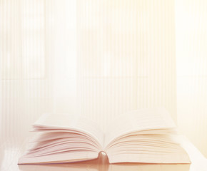 Open book on wood background with sunlight