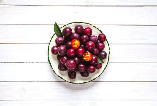Old plate with plums over board. Top view. Fruits background wit