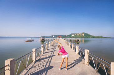 Obraz premium Healthy lifestyle. Jogging outdoors. Young slim woman exercising on the sea pier.