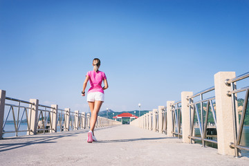 Healthy lifestyle. Jogging outdoors. Young slim woman exercising on the sea pier.