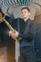 A young man in a suit standing with a saxophone musical instrument