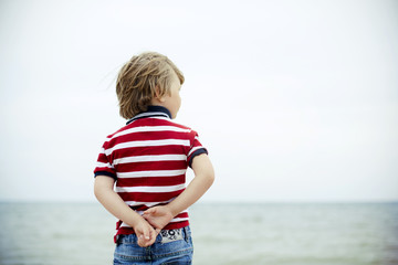 boy stands on the beach near sea or ocean