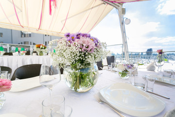 Closeup of vase with flowers on table served for banquet on rest
