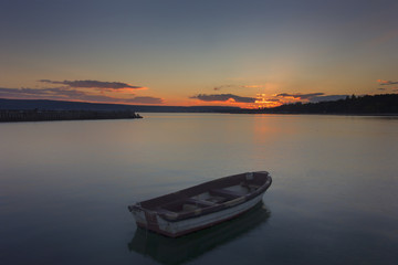 Beautiful light composition and mood of the boat in calm water at sunset