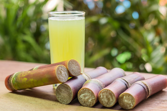Sugarcane juice with piece of sugarcane on wooden background