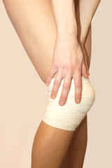 Woman holding hand on the bandaged knee.The concept of health.