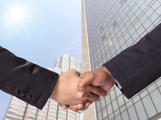 Hand shake between a businessman on Modern glass building backgr