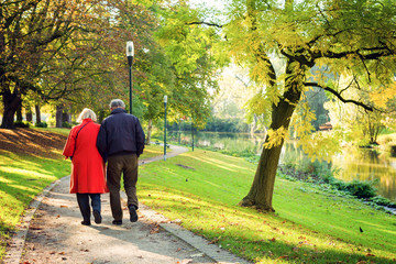Senior couple walking in a park in Bruges, Belgium on Sunny autumn morning. Autumn colors.