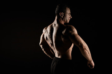 Obraz na płótnie Canvas torso of attractive male body builder on black background.
