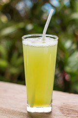Sugarcane juice with piece of sugarcane on wooden background
