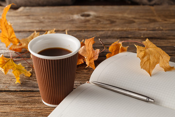Cup of tea with old book, autumn leaves on wooden table