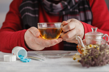 Man Cold / Ill man with scarf and tea cup, sneezing into handker